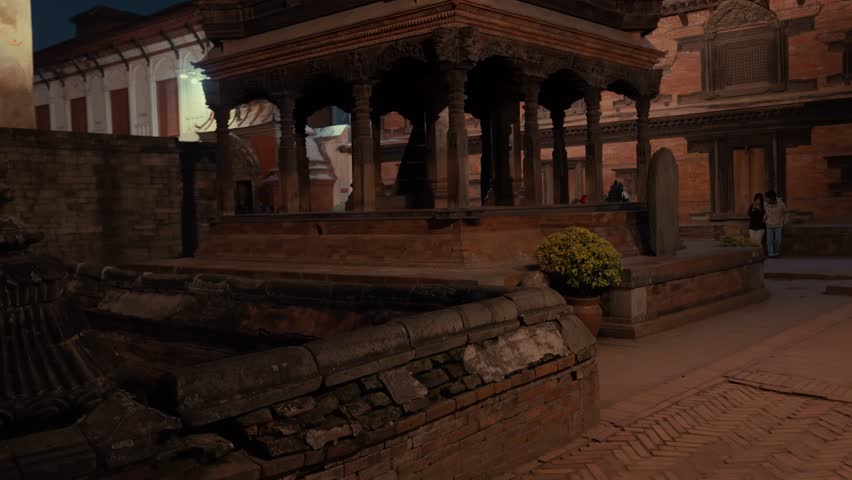 Temples and historic buildings at Bhaktapur Durbar Square lit by warm lights after sunset. Nepal