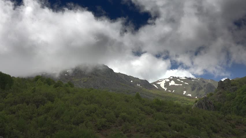Cinematic timelapse of mountain forest clouds forming from moist air condensation in Spain. Atmospheric fog develops across Iberian ranges as humid airflow lifts above wooded slopes.