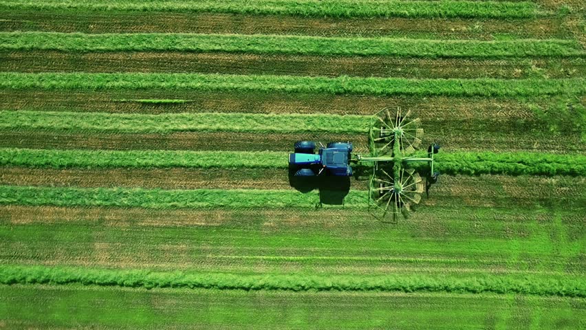 Aerial View of Agricultural Harvesting Process with a Tractor Tending to Lush Green Fields in Finland