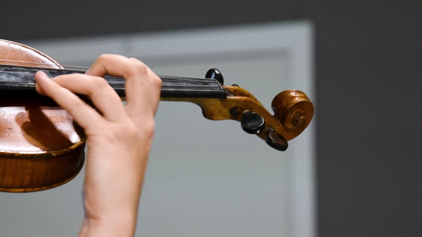Girl playing the violin, close-up. A musician uses a bow to play the violin. A performance or a musician