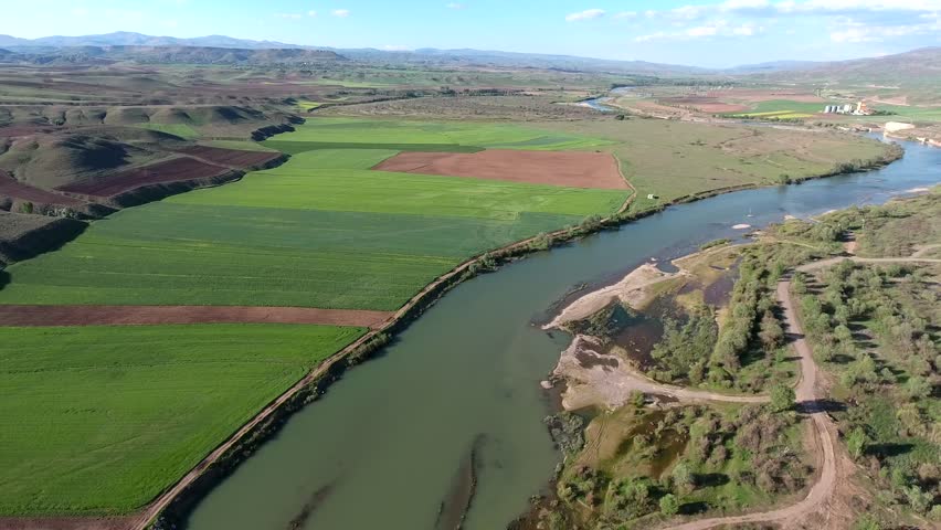 Aerial view of Mississippi River in USA America winding beside green farmland plains. Overhead panorama shows vast channel cutting across prairie cropland toward calm northern headwaters.