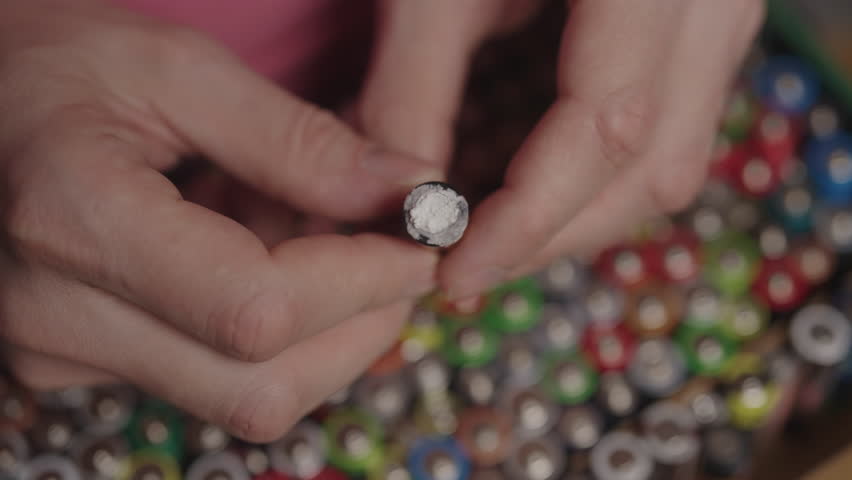 Person holding corroded AA battery with white powder residue, symbolizing hazardous waste from electronics and urgent need for responsible recycling to protect the environment, close-up, slow motion.