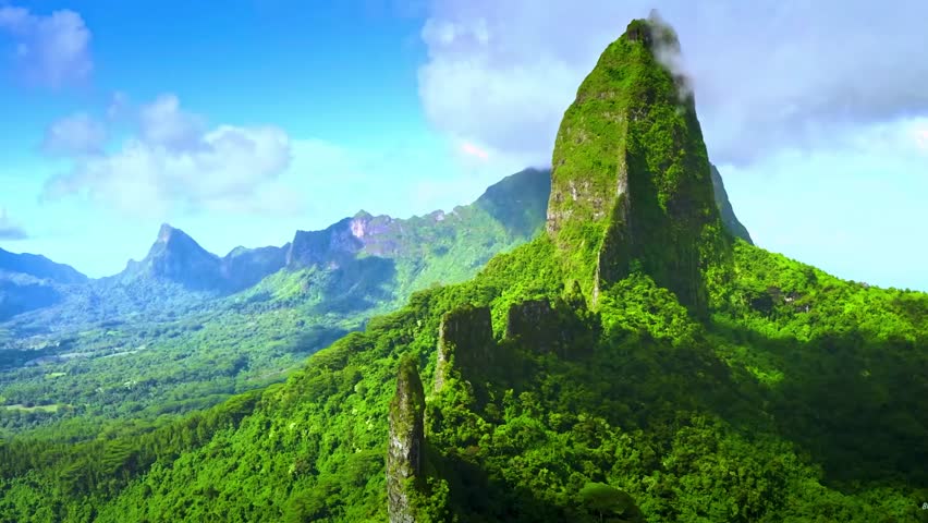 Mountain landscape with green grass and tall mountains under a bright blue sky with soft white clouds HD regulation video.