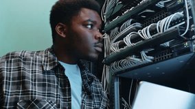 Young man works with server rack and network cables in a data center during daytime hours - Powered by Shutterstock - Get 15% off with code: PIKWIZARD15
