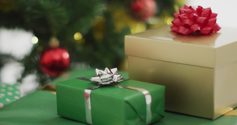 Animation of merry christmas text banner over close up of decorated christmas tree and gifts. Christmas festivity and celebration concept