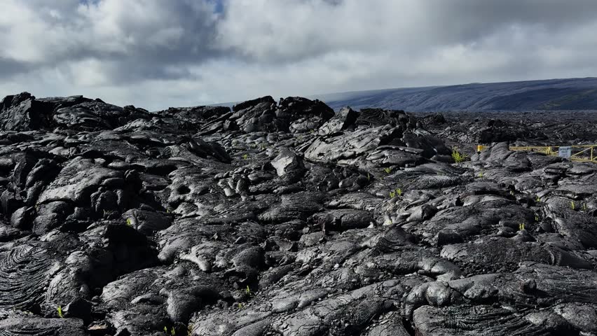 Panning view across vast dry lava flows under sunlight in Hawaii