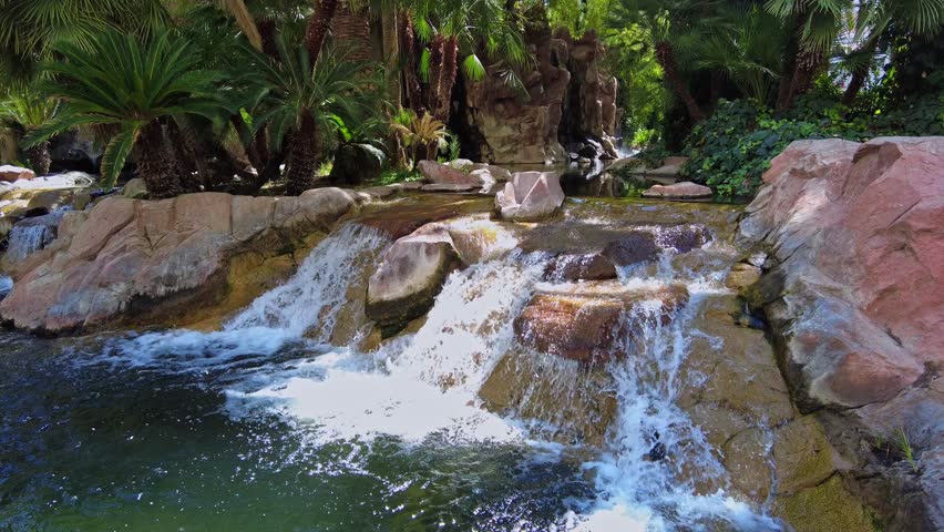 Decorative artificial waterfall flowing into garden pond with koi fish swimming in clear green water. Las Vegas. USA.