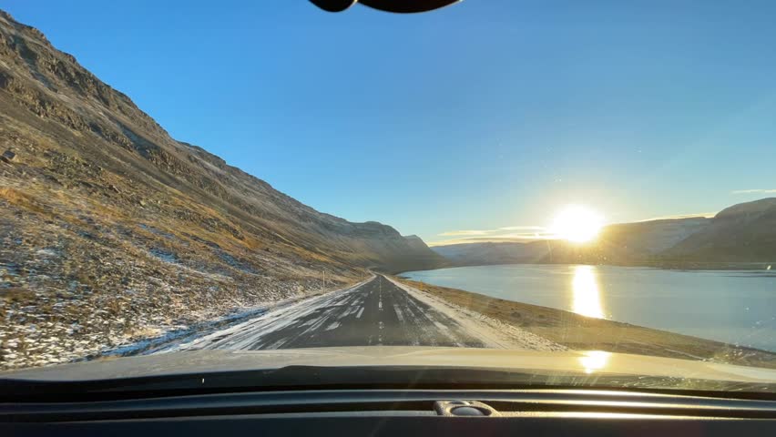 Breathtaking drive on road along water. Scenic landscape, mountains, and a stunning sunset. Use travel