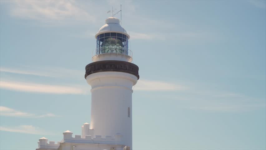 Wide view of the Byron Bay Lighthouse tower rising against a clear blue sky, showing the full upper structure and lantern room during daytime, Byron Bay, Australia.