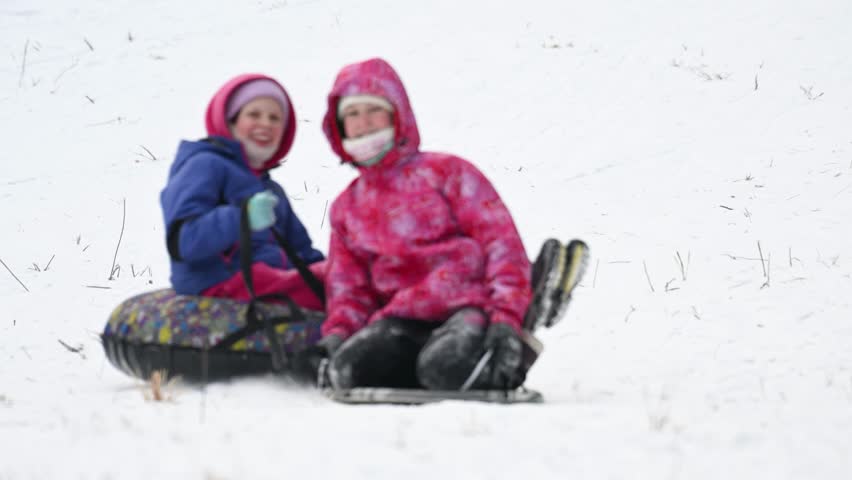 Happy children sledding down a snowy slope. Slow motion.