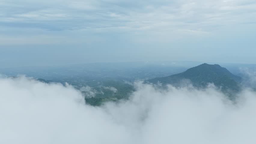 Stunning aerial perspective from turyapada tower in bali, indonesia. Misty clouds moving over lush green mountains and tropical rainforest