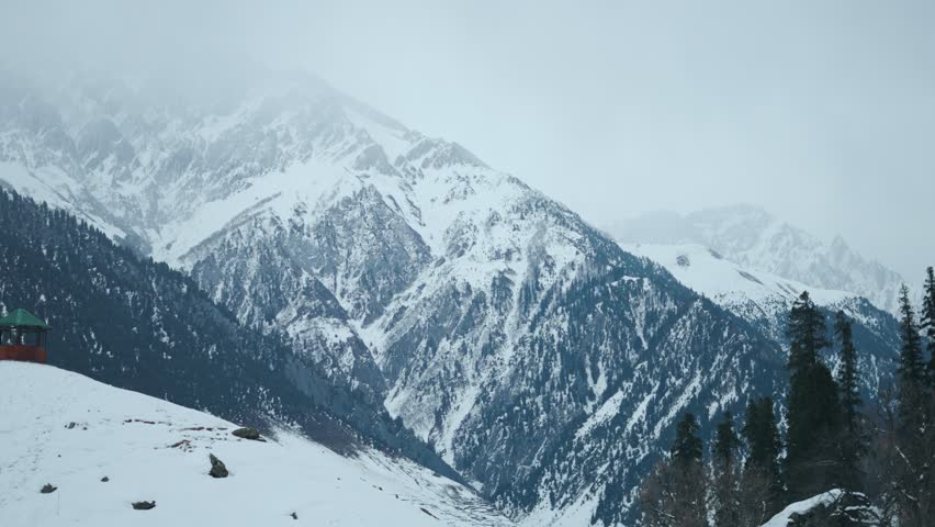 4K Landscape shot of snowy Himalayan mountain peaks with trees on top during the winter season as seen from Sonmarg in Jammu and Kashmir, India. Scenic view of Pir Panjal range in winter season.