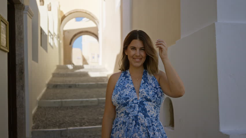 Woman looking up with exposed shoulders on santorini street, smiling at sky; summer travel vacation serenity.