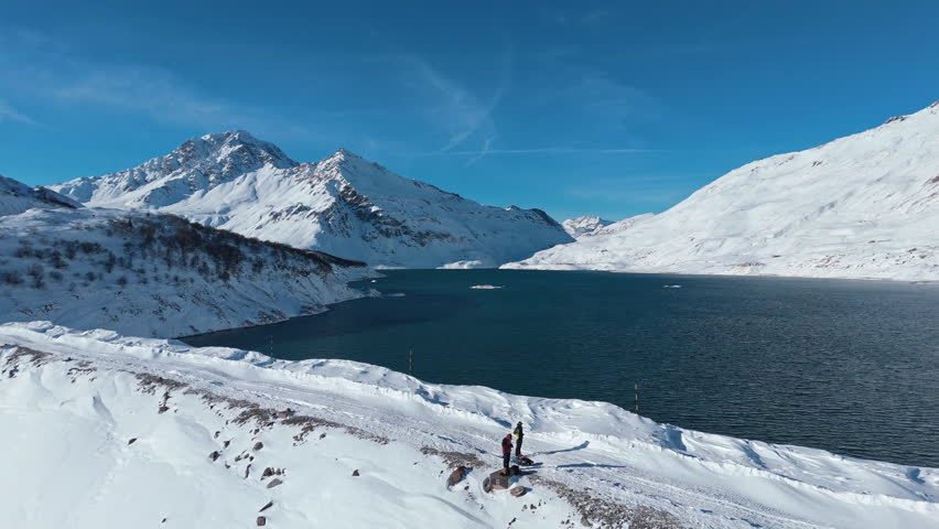 Snowy mountains and lake under clear blue sky, serene winter landscape