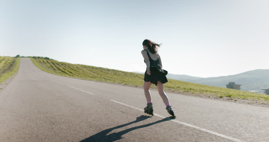 Sporty woman in black dress roller blading on road
