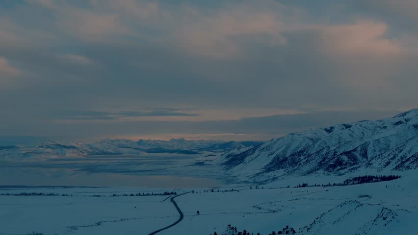 Mono Lake, California with Sierra Nevada snowy mountains reflected across a turquoise saline lake at golden hour, glowing pink, orange, and purple sky over a serene Eastern Sierra desert panorama. 4K 