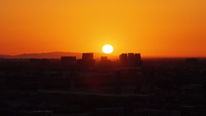 Aerial view of urban city skyline with silhouette of buildings at an orange sunset