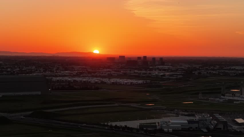Aerial view of urban Orange County city skyline with silhouette of buildings during an orange sunset.