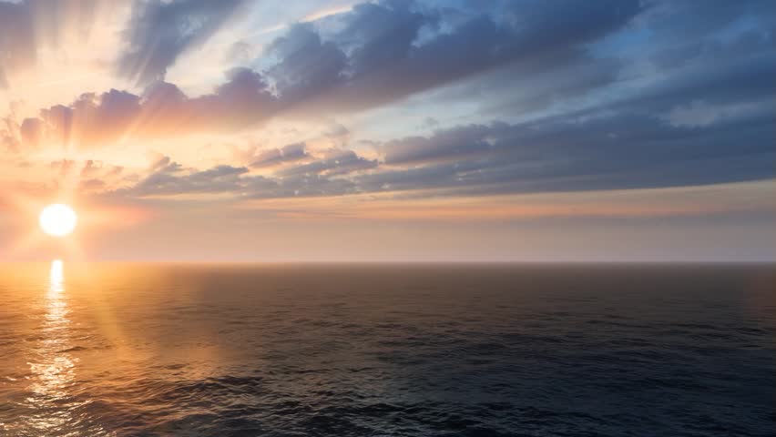A magnificent golden sun sets directly over the vast ocean horizon, casting bright crepuscular rays through dramatic layered clouds across the colorful sky.