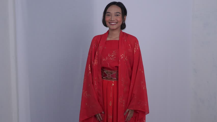 Asian woman dressed in red hanfu, smiling while pointing to the side