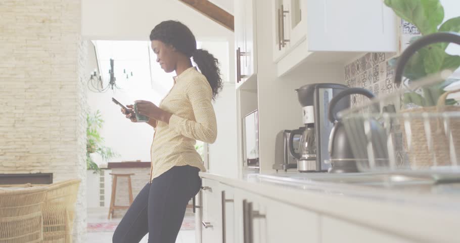 Woman leaning on counter holding phone and mug, phone initiating expanding pink graphic for tech. Kitchen, home, modern, casual, lifestyle, digital, overlay