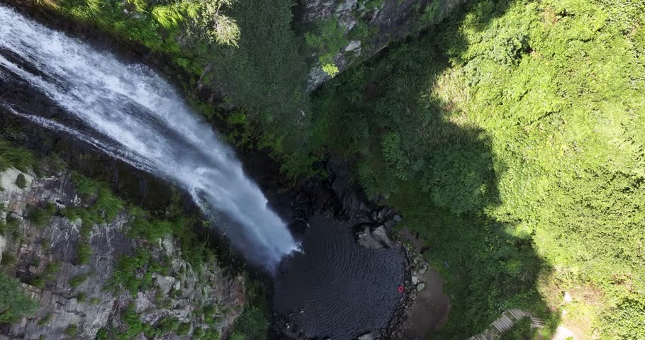 Aerial drone hover shot of Jade Curtain Waterfall (Yu Lian Spring) on Mount Lu, Overhead view captures plunging cascade amid cliffs, forest, and serene pool.  Jiangxi Province, China.