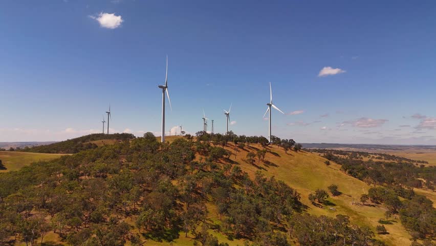 Aerial establishing of wind turbines aligned across dry rolling hills under clear blue sky in Australia, ascend, Cullerin