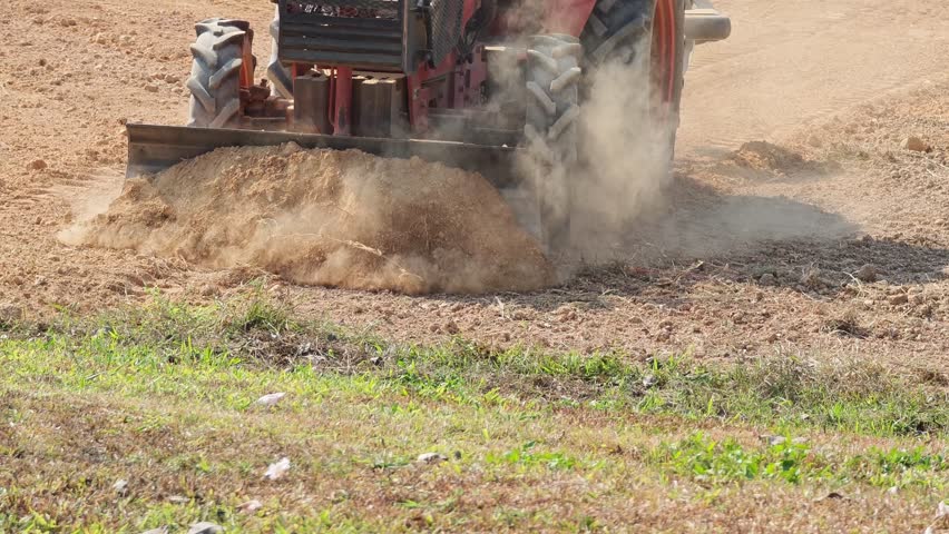 The tractor is plowing and preparing the land for planting crops.