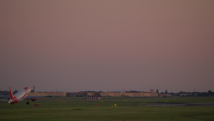 Airplane taking off into dusky sky at airport runway with lights on tarmac