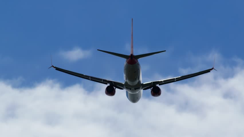 View from below of commercial airplane ascending into clouds in blue sky footage