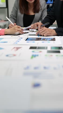 Business professionals collaborate on a project, analyzing financial data, discussing strategies, and working together in a modern office.