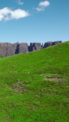Green Hillside Beneath Blue Sky. Peaceful Rolling Green Hills Topped With Rugged Cliffs And Clouds. Media