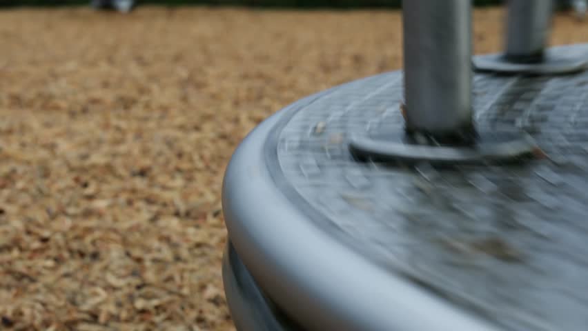 Low angle close up shot of a spinning Children’s Merry go round in an outdoor playground