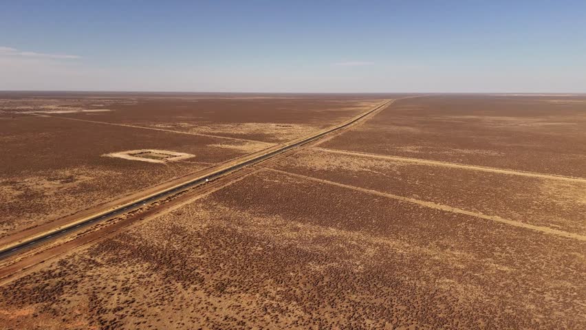 Hay Plains intersecting dirt tracks crossing wide dry plains under pale sky, empty arid backdrop, NSW Australia