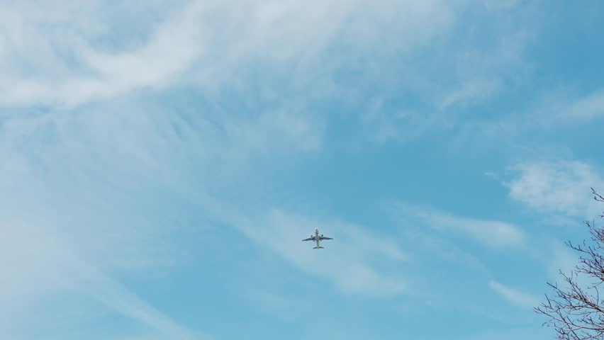 A passenger plane crosses a clear blue sky, dynamic aerial motion of jet aircraft on sunny day, transporting people for international travel