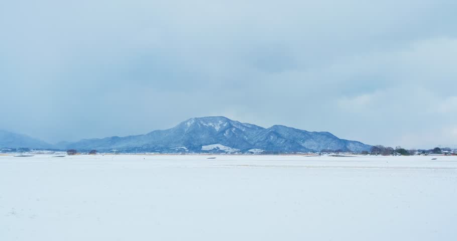 Snowy Rural Japan Landscape with Kakudayama Mountain, Winter Rice Fields and Cloudy Sky