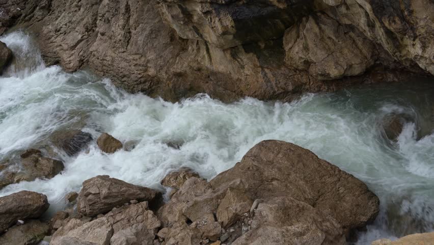 Rushing water splashing against river stones in a high mountain valley for beautiful adventure film scenes