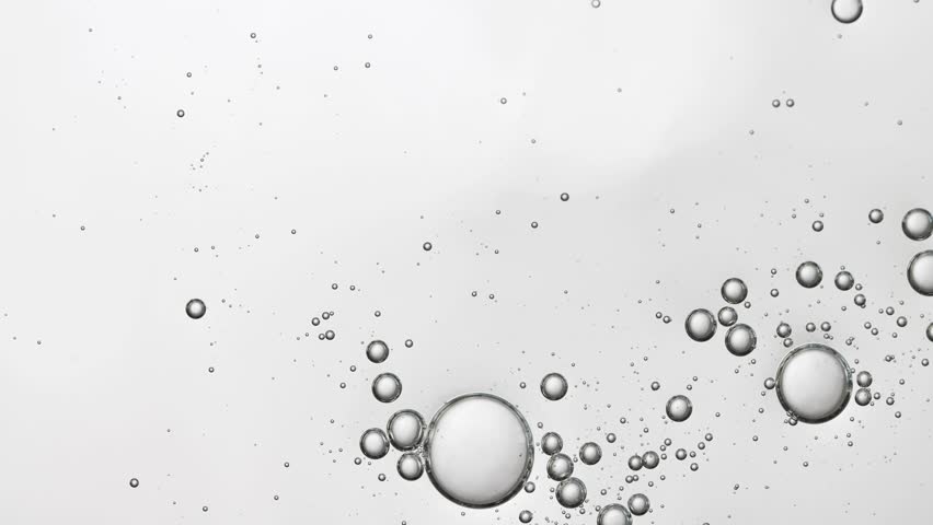 Transparent liquid texture of care product with bubbles, top view, slow movement of the product.