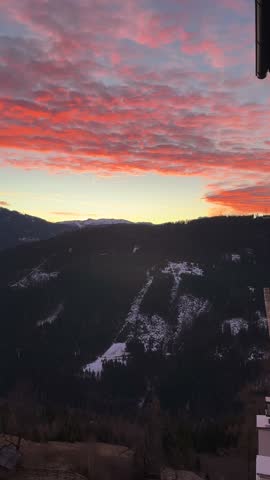 Sunlight reflects off the mountains, creating a stunning red glow across Austria’s natural landscape at sunset.