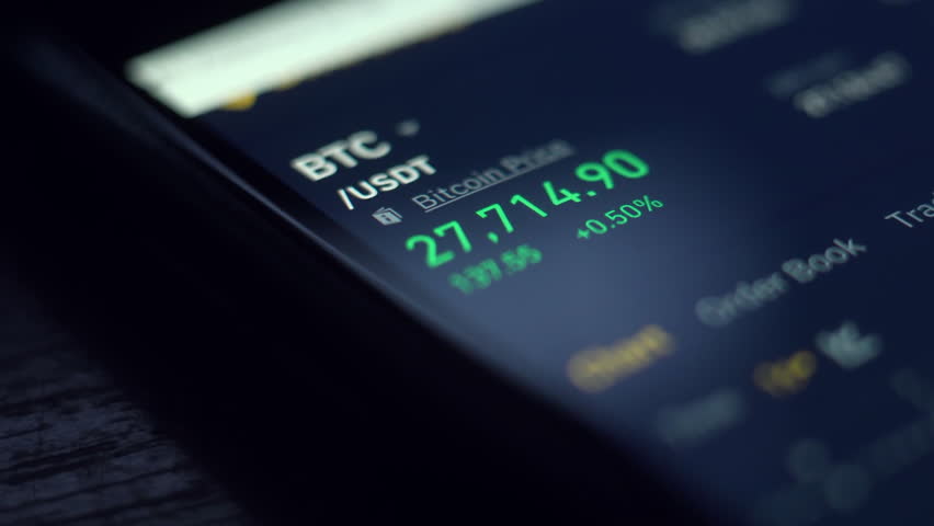 A close-up view of a smartphone screen displaying the current price of Bitcoin in USDT, highlighting market fluctuations with green and red indicators.