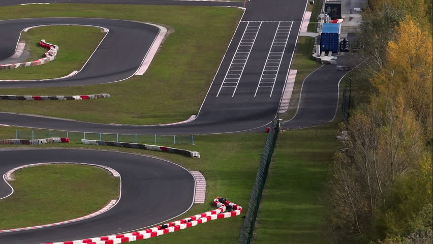 Closeup of empty race track surrounded by trees and fields during bright daylight.