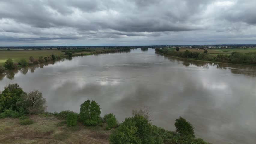 Expansive view of the Trebbia river merging with the Po River under a dramatic cloudy sky in the Emilia Romagna region of Italy near Borgotrebbia