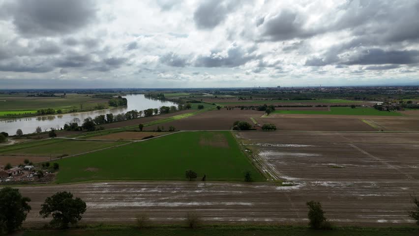 Expansive view of the Trebbia river merging with the Po River under a dramatic cloudy sky in the Emilia Romagna region of Italy near Borgotrebbia