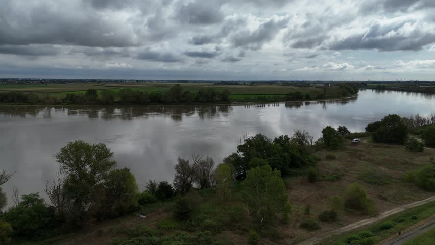 Expansive view of the Trebbia river merging with the Po River under a dramatic cloudy sky in the Emilia Romagna region of Italy near Borgotrebbia