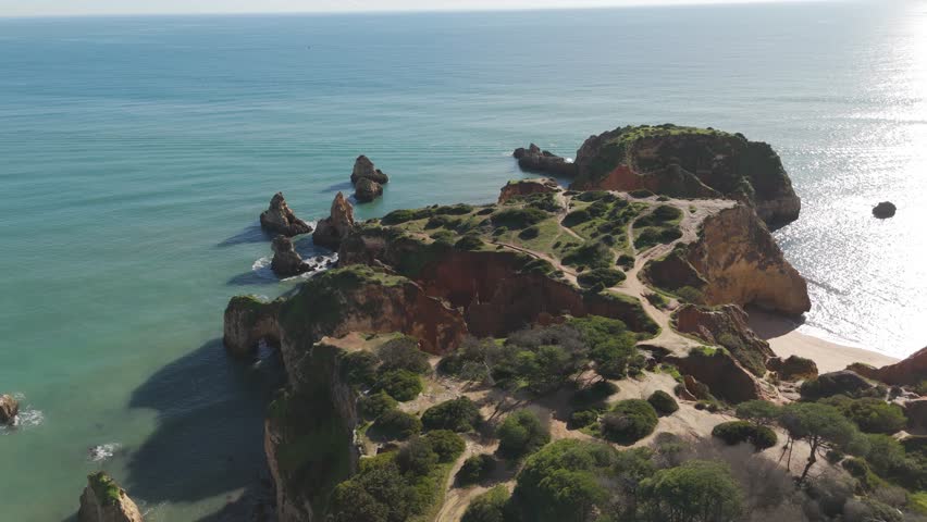 Scenic coastal landscape showcasing rocky cliffs, natural vegetation, and ocean waters along the Algarve coast.