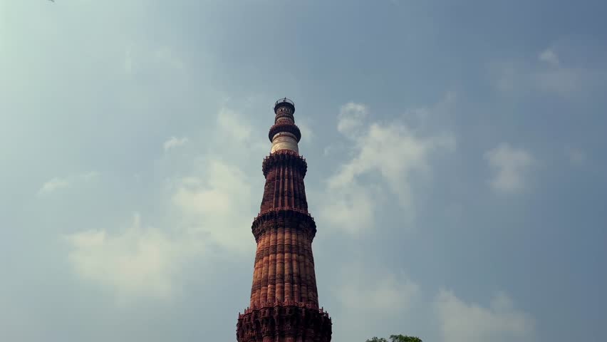 A shot of Qutub Minar in Delhi India with Airplane Flying Overhead