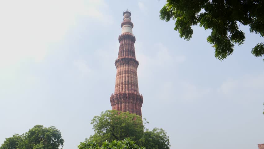 A shot of Qutub Minar in Delhi India with Airplane Flying Overhead
