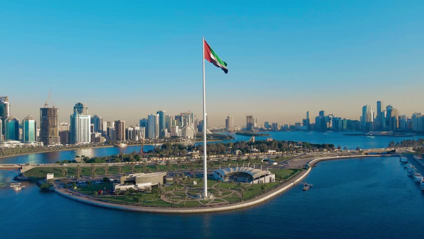 Aerial view of the UAE flag waving gracefully, the national symbol of the United Arab Emirates. High-resolution drone footage highlighting patriotic colors, national pride, and iconic symbolism for celebrations, events, and media projects.