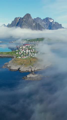 Stunning aerial footage of Reine village on the Lofoten Islands, Norway, emerging from the morning fog