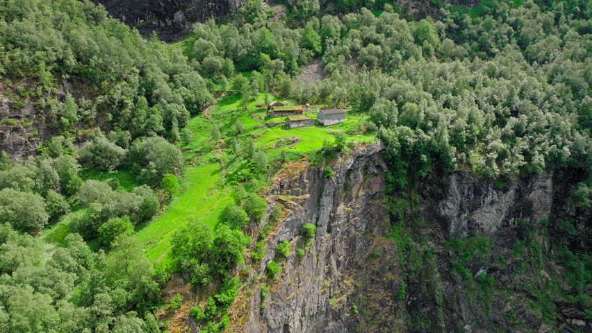 Drone view of grassy paths at Skageflå overlooking the Norwegian fjord landscape in Norway. Peaceful daylight emphasizes steep cliffs, forested slopes, and historic mountain farming.